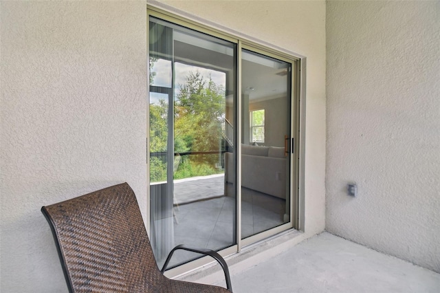 view of exterior entry featuring a balcony and stucco siding