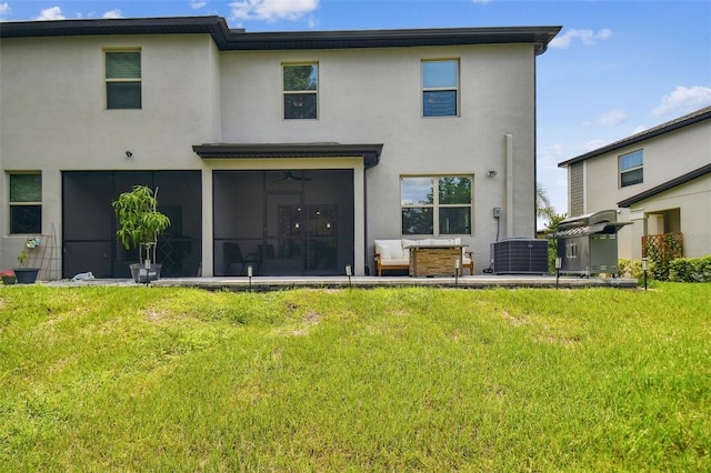 rear view of house with a sunroom, a yard, central air condition unit, and stucco siding