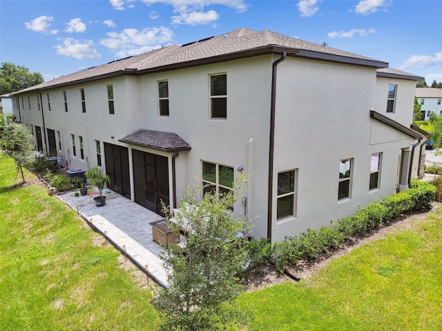 back of property featuring a sunroom, a patio area, a yard, and stucco siding