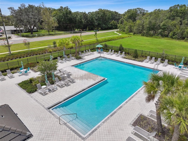 pool with a patio, a lawn, and fence