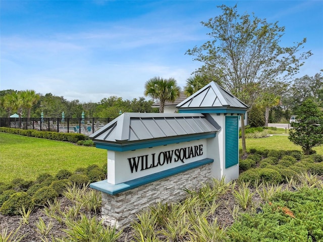 community / neighborhood sign featuring fence and a yard