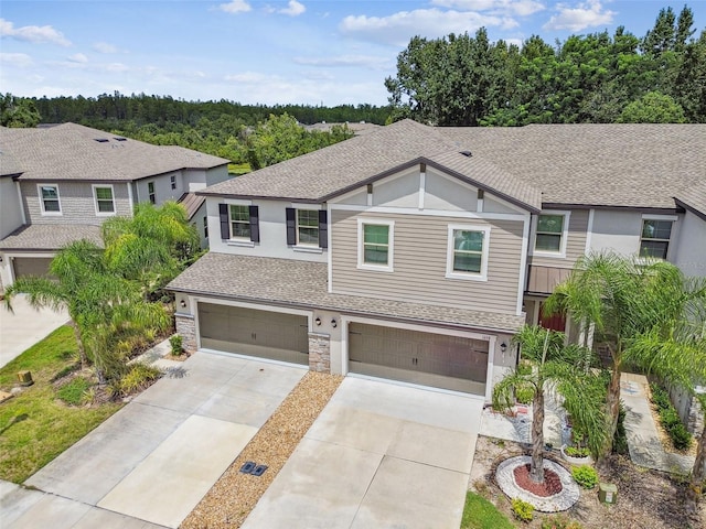 view of front of house featuring a garage, stone siding, concrete driveway, and roof with shingles