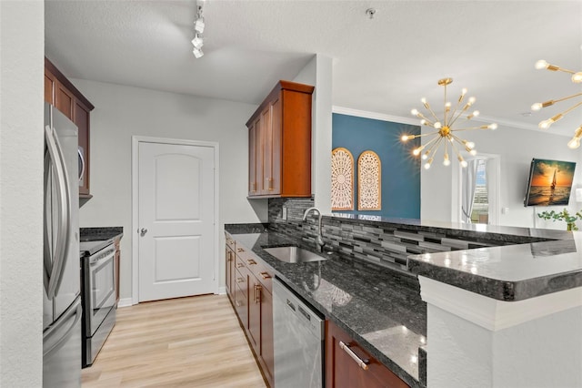 kitchen featuring backsplash, sink, ornamental molding, light wood-type flooring, and stainless steel appliances