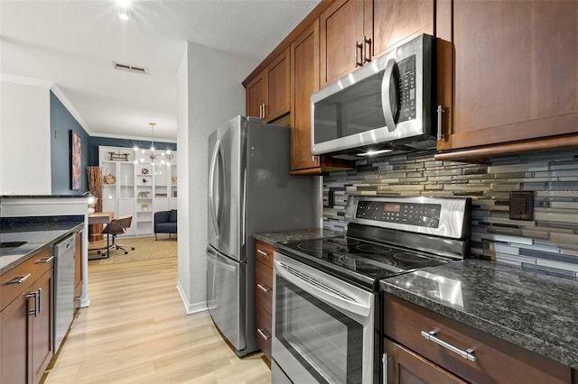 kitchen featuring backsplash, appliances with stainless steel finishes, light hardwood / wood-style floors, dark stone countertops, and decorative light fixtures