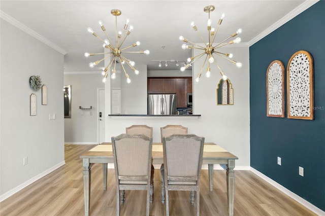 dining area with light hardwood / wood-style floors, rail lighting, an inviting chandelier, and ornamental molding