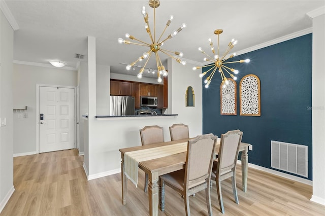 dining room featuring an inviting chandelier, light hardwood / wood-style flooring, and ornamental molding