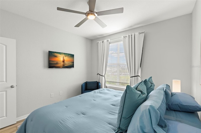 bedroom featuring ceiling fan, multiple windows, and hardwood / wood-style floors