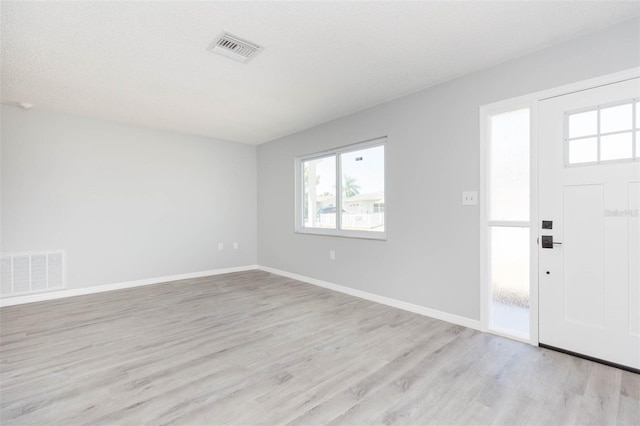 foyer with light wood-type flooring and a textured ceiling