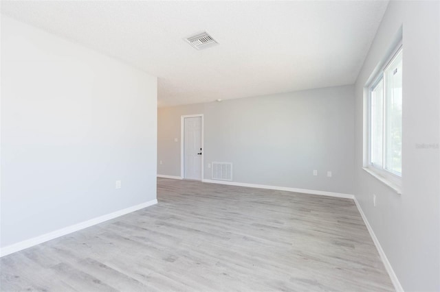 spare room featuring a textured ceiling and light hardwood / wood-style floors