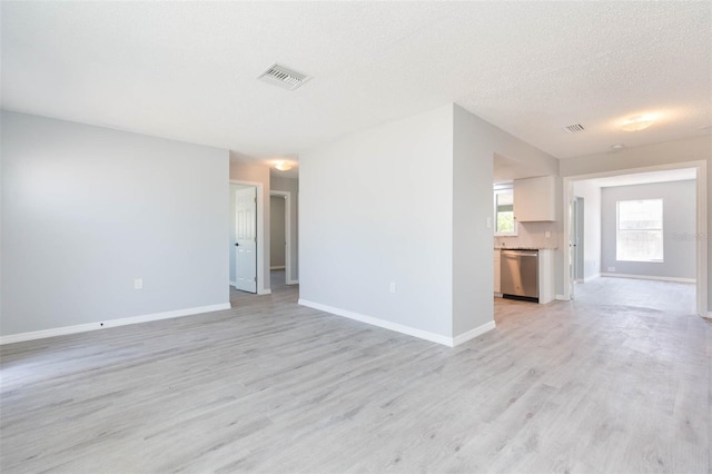 unfurnished living room featuring light wood-type flooring and a textured ceiling