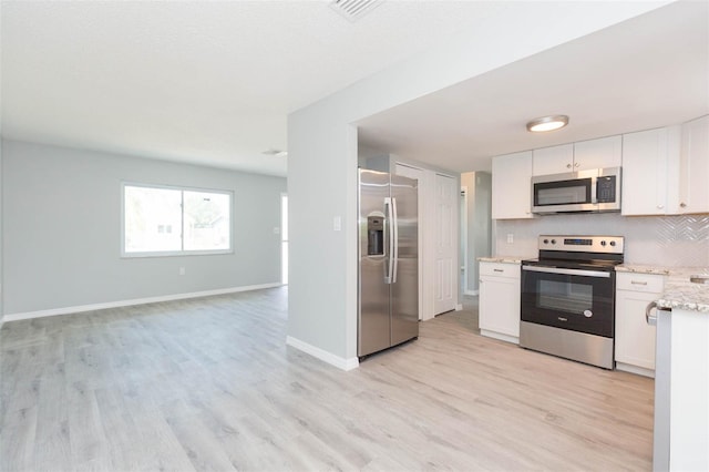 kitchen with light hardwood / wood-style flooring, light stone counters, stainless steel appliances, and white cabinets