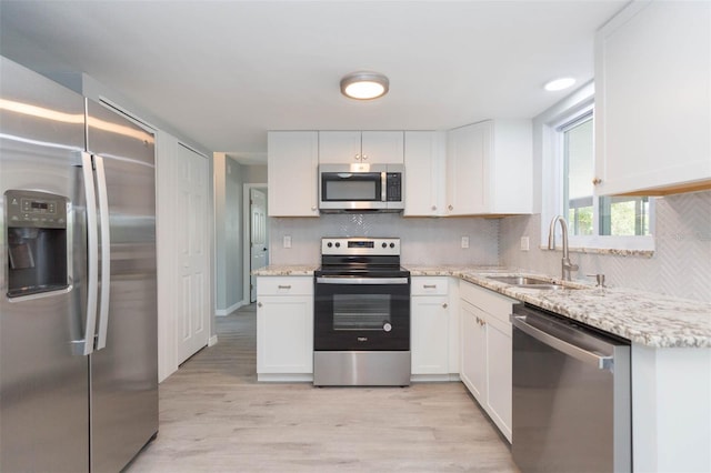 kitchen featuring light stone counters, sink, appliances with stainless steel finishes, white cabinets, and light hardwood / wood-style floors