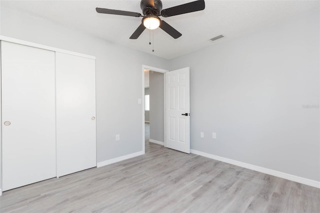 unfurnished bedroom featuring a textured ceiling, light hardwood / wood-style flooring, ceiling fan, and a closet