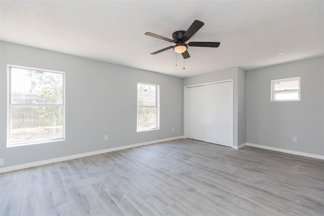 unfurnished bedroom featuring a closet, ceiling fan, light hardwood / wood-style floors, and a textured ceiling