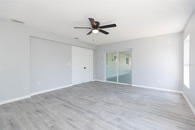 empty room with a textured ceiling, ceiling fan, and light hardwood / wood-style floors