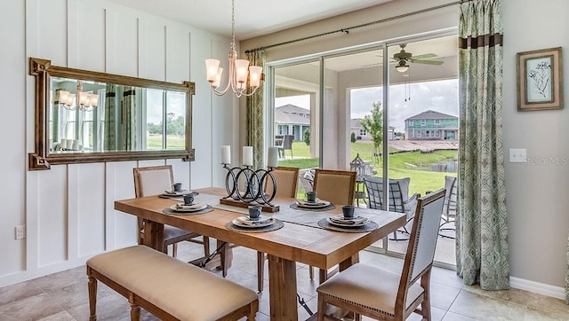 dining space featuring ceiling fan with notable chandelier, a decorative wall, plenty of natural light, and baseboards