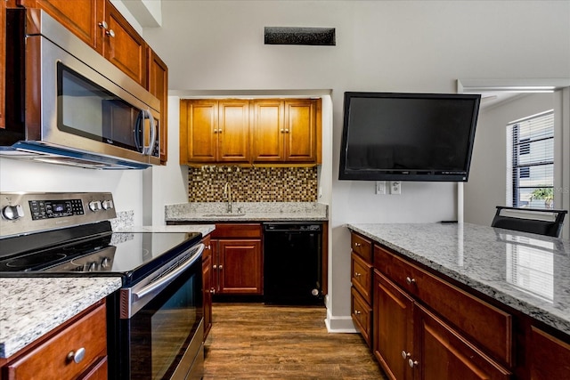 kitchen with backsplash, wood-type flooring, appliances with stainless steel finishes, light stone counters, and sink