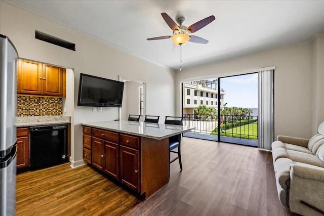 kitchen with ceiling fan, dark wood-type flooring, tasteful backsplash, dishwasher, and a breakfast bar area