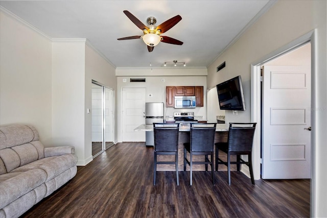 kitchen featuring a kitchen bar, appliances with stainless steel finishes, dark hardwood / wood-style floors, ceiling fan, and kitchen peninsula