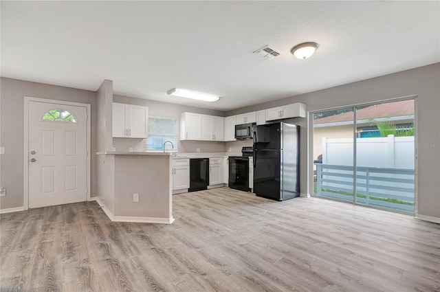 kitchen featuring light hardwood / wood-style floors, white cabinets, sink, and black appliances