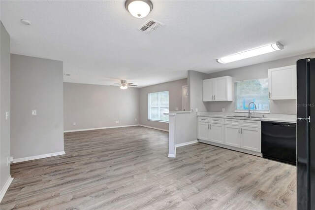 kitchen featuring light hardwood / wood-style floors, white cabinets, black appliances, and a healthy amount of sunlight