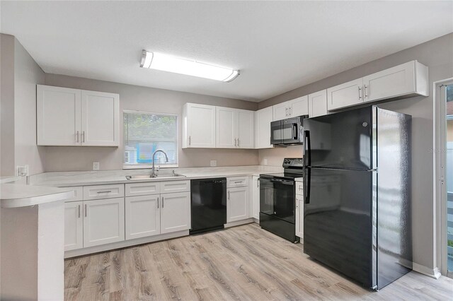 kitchen featuring sink, white cabinetry, black appliances, and light hardwood / wood-style floors