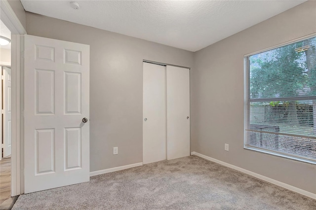 unfurnished bedroom featuring a closet, light carpet, and a textured ceiling