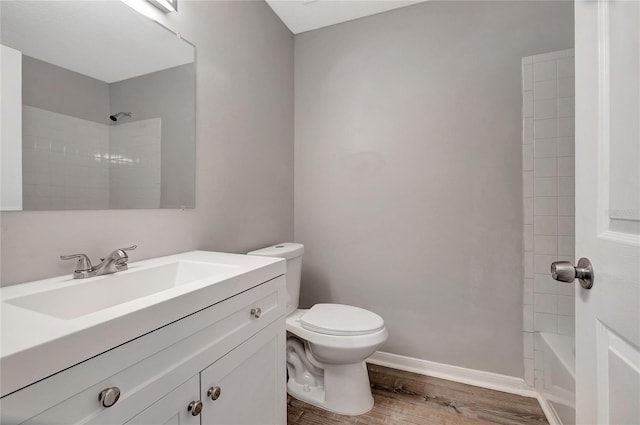 full bathroom featuring wood-type flooring, toilet, tiled shower / bath, and vanity