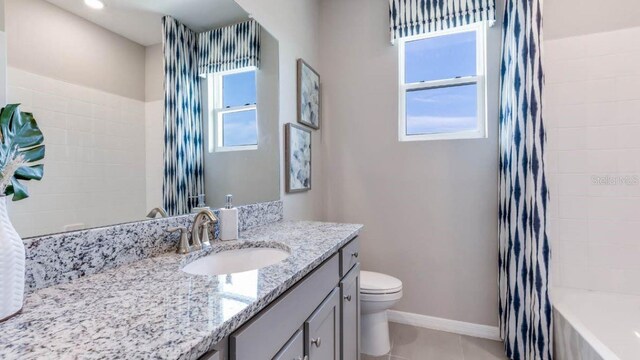 bathroom featuring toilet, vanity, baseboards, and tile patterned floors