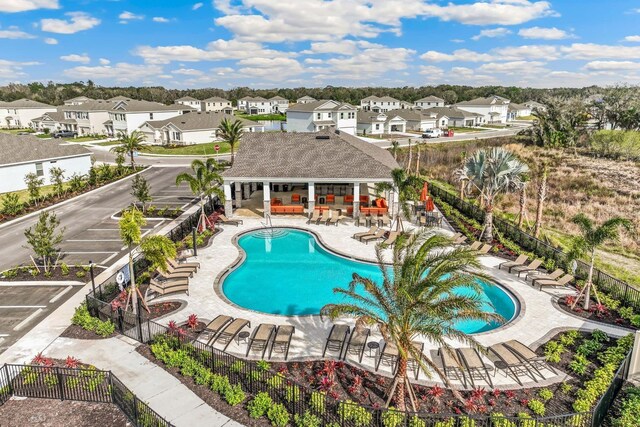 community pool with a patio area, fence, and a residential view