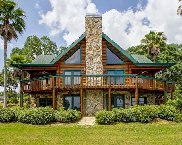 back of property with stone siding, a yard, and a deck