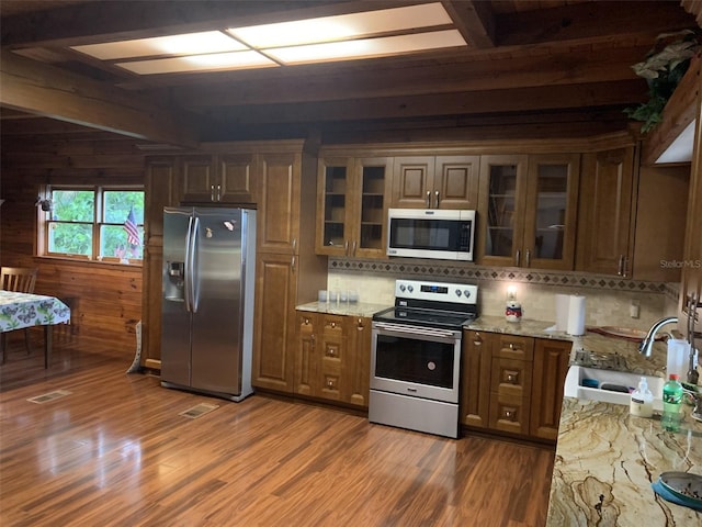 kitchen featuring appliances with stainless steel finishes, glass insert cabinets, and light stone counters