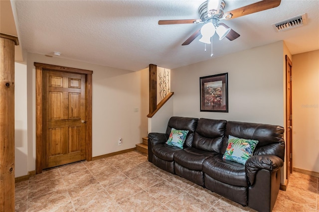 living area with visible vents, ceiling fan, a textured ceiling, and baseboards