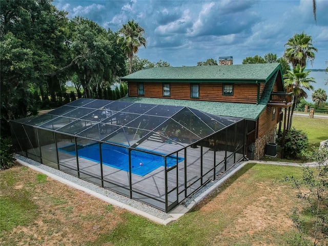 outdoor pool featuring a patio area, a lawn, cooling unit, and a lanai