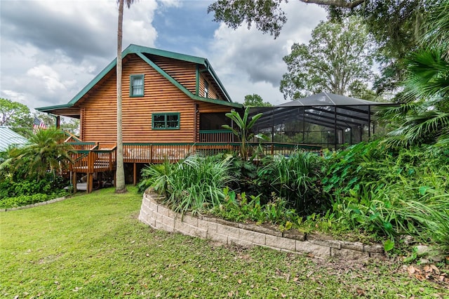 back of house with a deck, a lawn, and a lanai