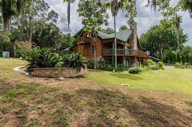 back of property featuring stone siding, a yard, and a chimney