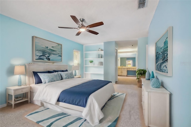 bedroom featuring light colored carpet, ceiling fan, and ensuite bath