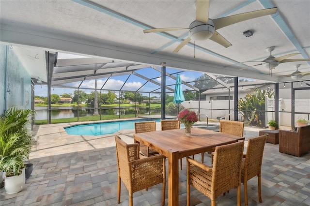 view of pool featuring glass enclosure, ceiling fan, a patio, and a water view