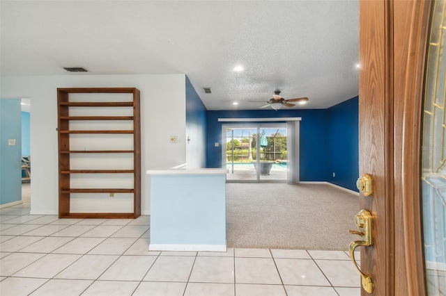 unfurnished living room featuring ceiling fan, light tile patterned floors, and a textured ceiling