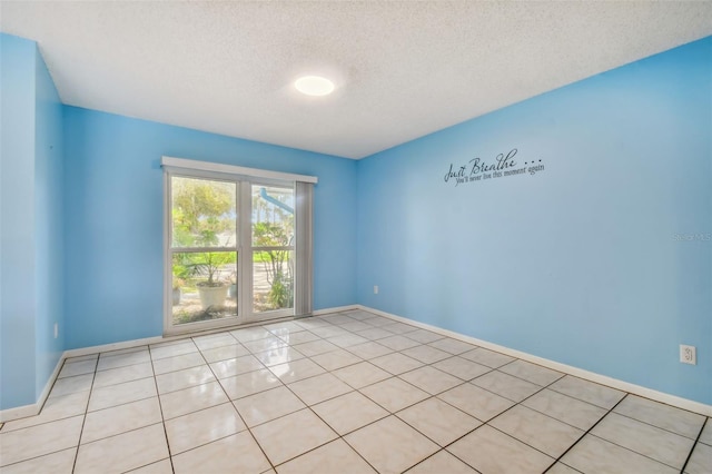 empty room featuring a textured ceiling and light tile patterned floors