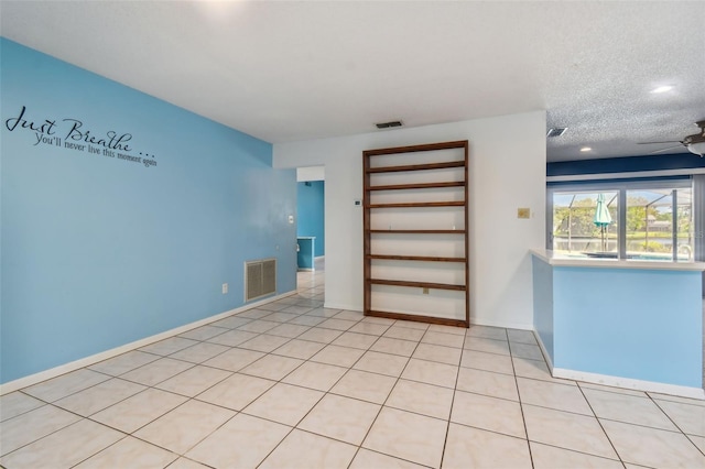 tiled spare room featuring a textured ceiling and ceiling fan