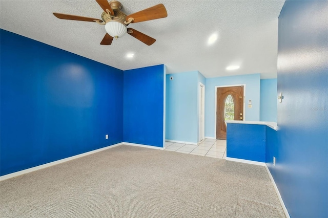 unfurnished room with a textured ceiling, ceiling fan, and light carpet