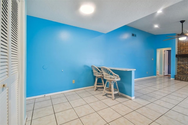 unfurnished dining area with ceiling fan, light tile patterned floors, and a textured ceiling