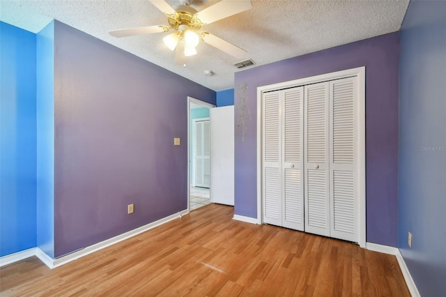 unfurnished bedroom featuring a textured ceiling, hardwood / wood-style flooring, ceiling fan, and a closet