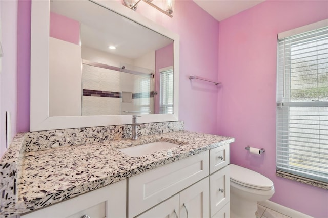 bathroom with a wealth of natural light, vanity, toilet, and walk in shower