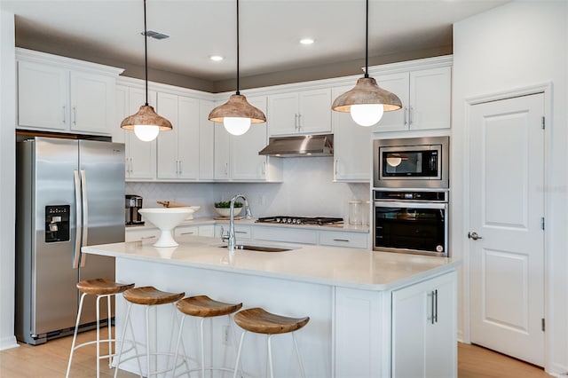 kitchen with light wood-type flooring, backsplash, white cabinets, appliances with stainless steel finishes, and sink