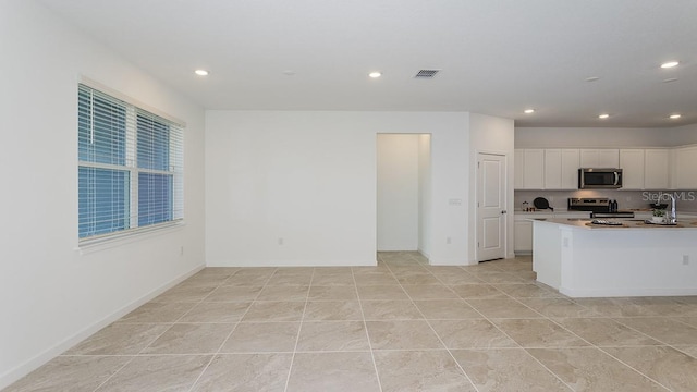 kitchen with stainless steel appliances, a kitchen island, and white cabinets