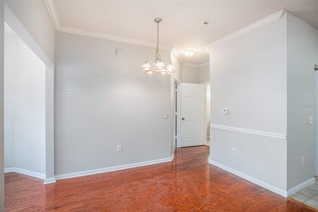 empty room featuring a chandelier, ornamental molding, and hardwood / wood-style flooring