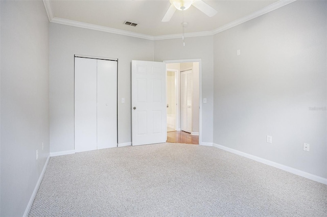 unfurnished bedroom featuring carpet floors, ceiling fan, crown molding, and a closet