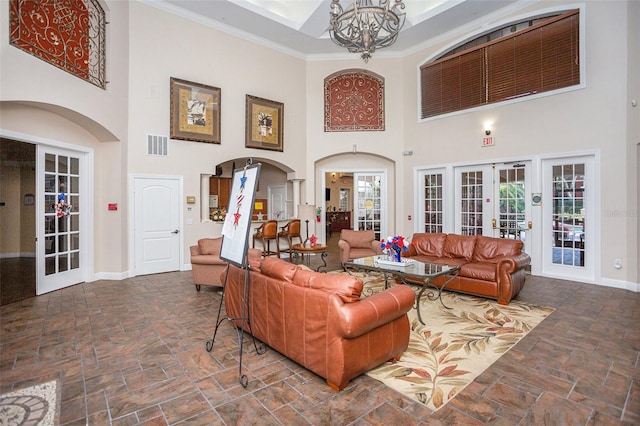 living room featuring a high ceiling, a notable chandelier, crown molding, and french doors